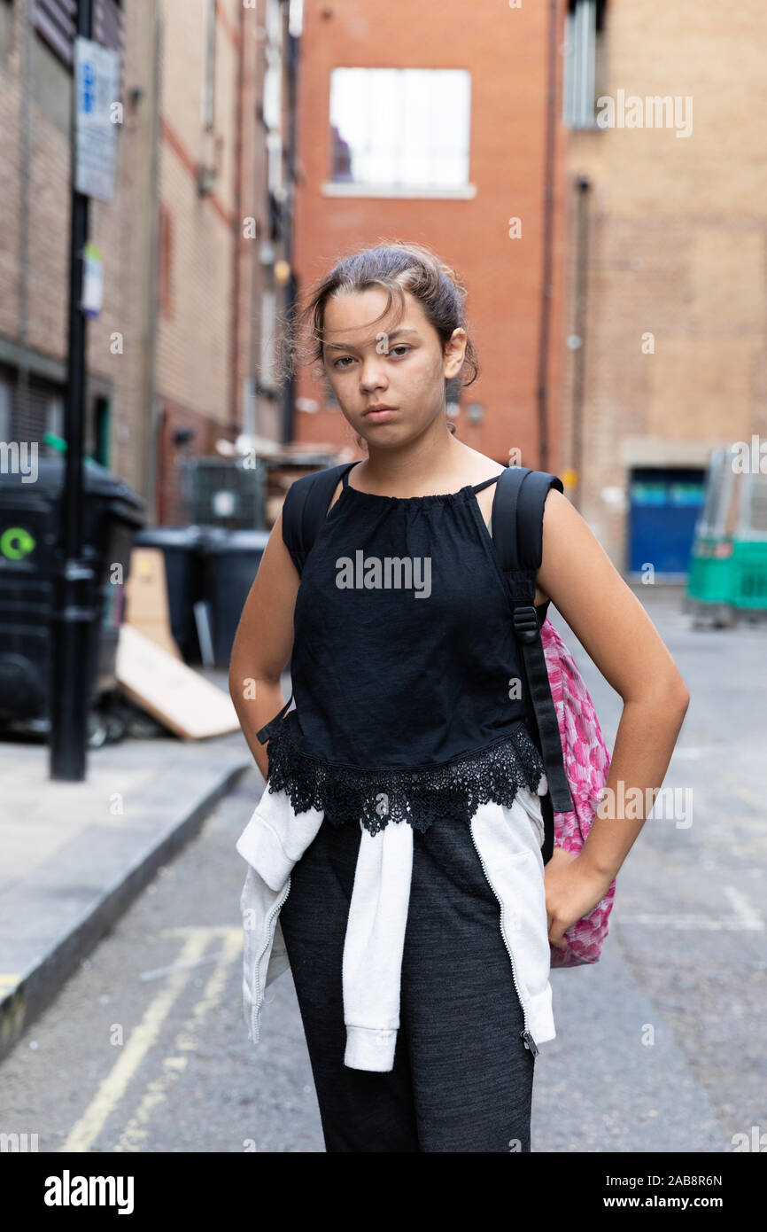 Ritratto di una giovane ragazza in un vicolo pieno di spazzatura. Un abbigliamento informale. Contesto urbano Foto Stock