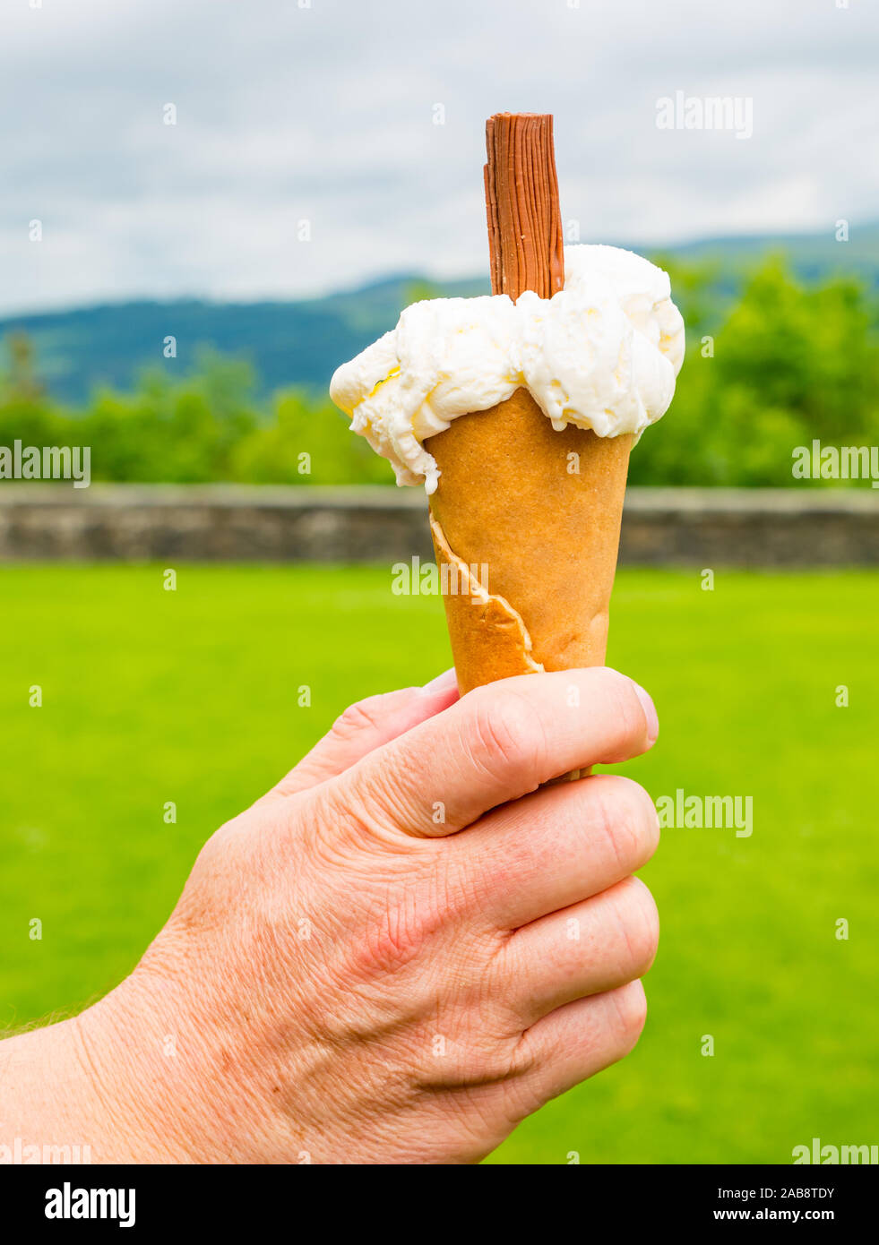 Maschio di mano azienda gelato alla vaniglia cono, il Castello di Stirling esplanade, Scotland, Regno Unito Foto Stock