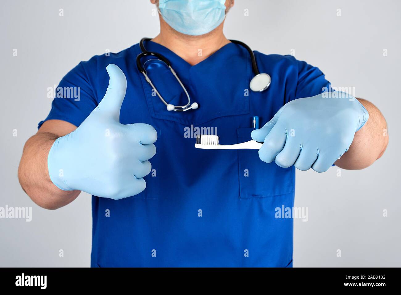 Dottore in sterili Guanti in lattice e blu uniforme tenendo uno spazzolino  da denti, igiene orale concetto Foto stock - Alamy