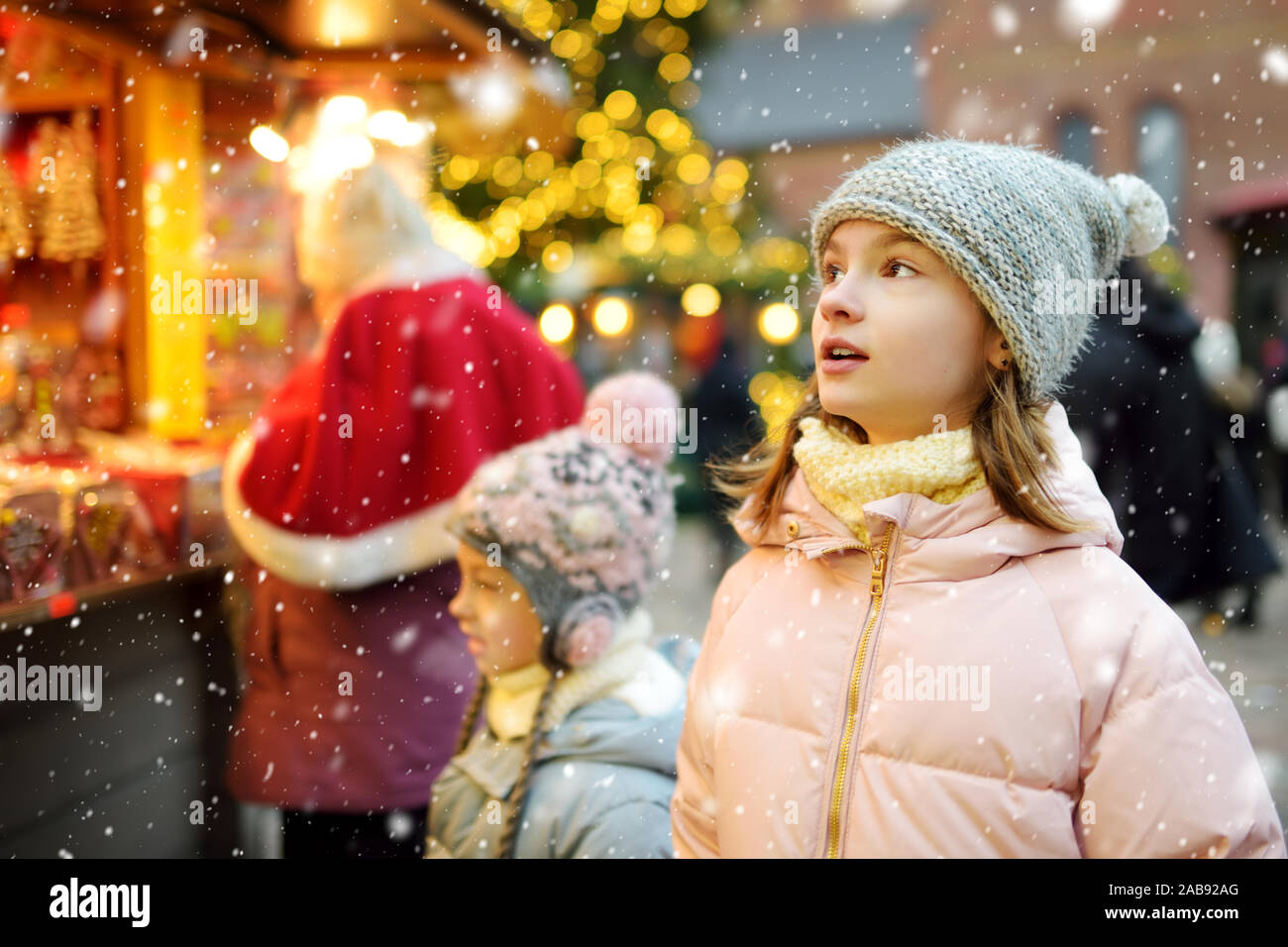 Carino giovani sorelle la scelta di dolci il tradizionale mercatino di Natale a Riga, Lettonia. Bambini acquisto di caramelle e biscotti sul Natale. La famiglia felice in tempo freddo Foto Stock