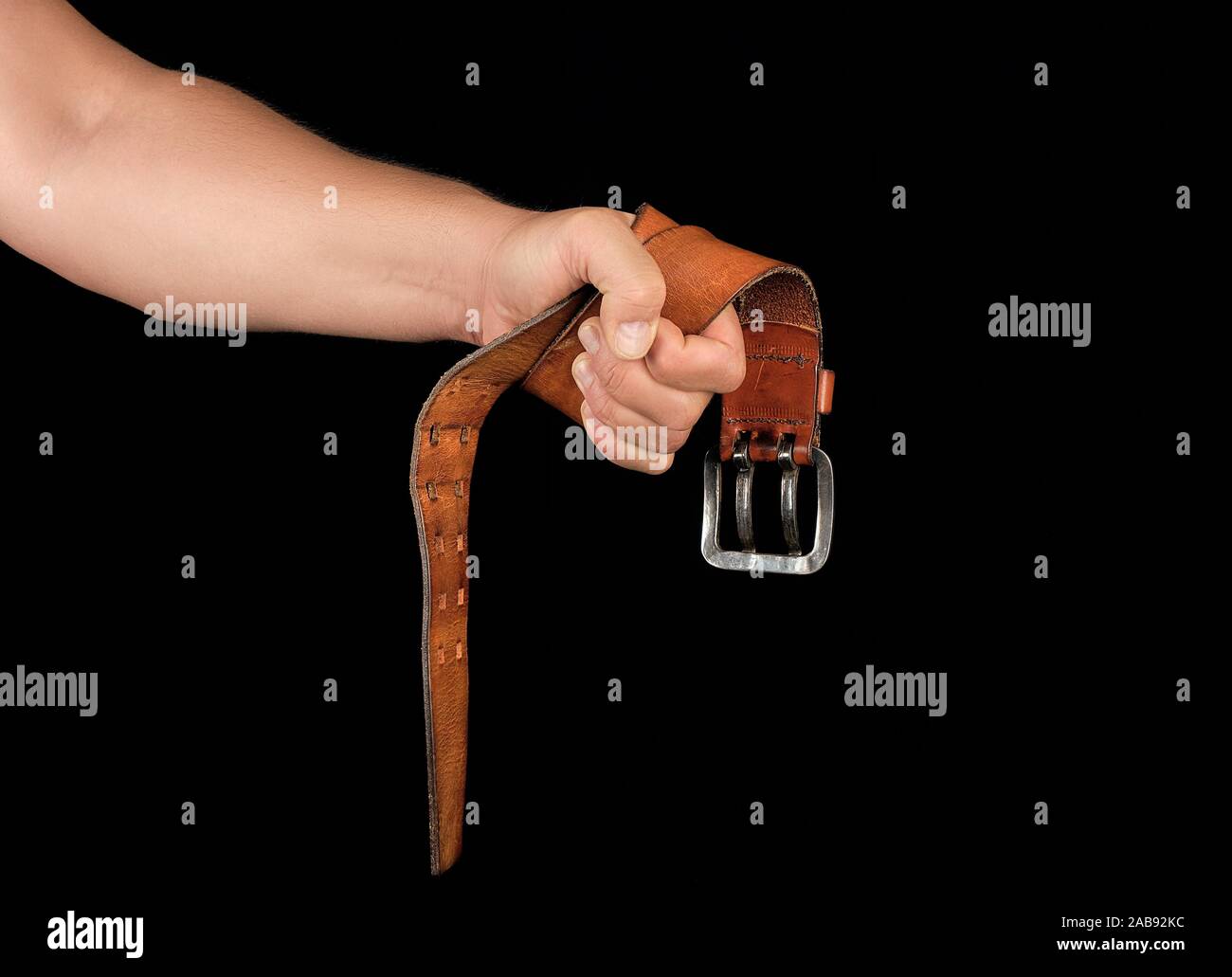 Brown cintura in cuoio con una fibbia di ferro in una mano d'uomo, sfondo  nero , concetto di aggressione Foto stock - Alamy