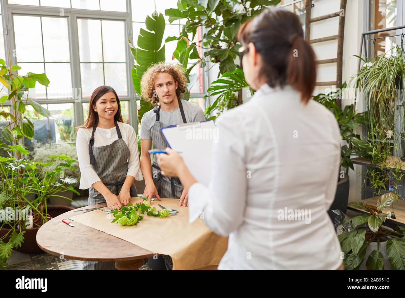 Due fioristi esame per completare il corso di addestramento in un negozio di fiori Foto Stock