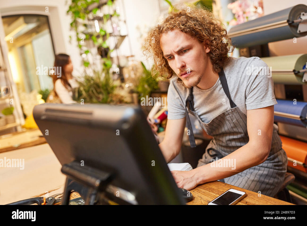 Giovani fioraio presso il computer in negozio di fiori come un negozio online Foto Stock