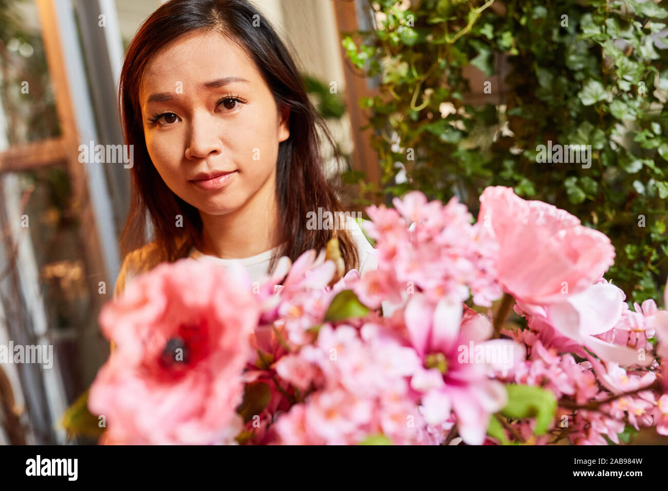 Giovane donna asiatica come un fiorista cravatte fiori freschi per bouquet in rosa Foto Stock
