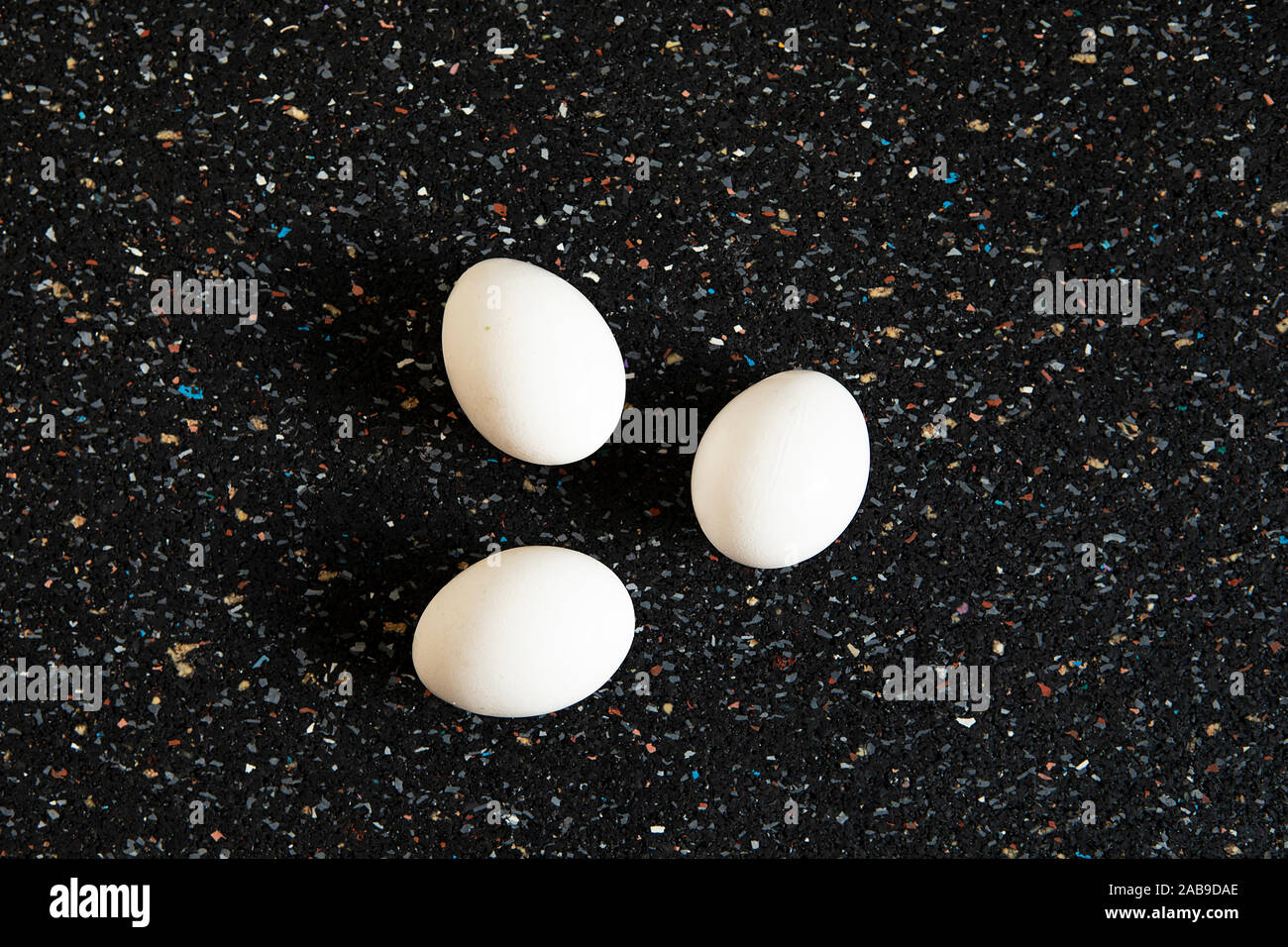 Disposizione astratta con uova di albero giace sul nero lo sfondo a chiazze. Bianco minimalista uova piatto ancora laici vita, cibo arte. La Pop art style. Nuova vita c Foto Stock