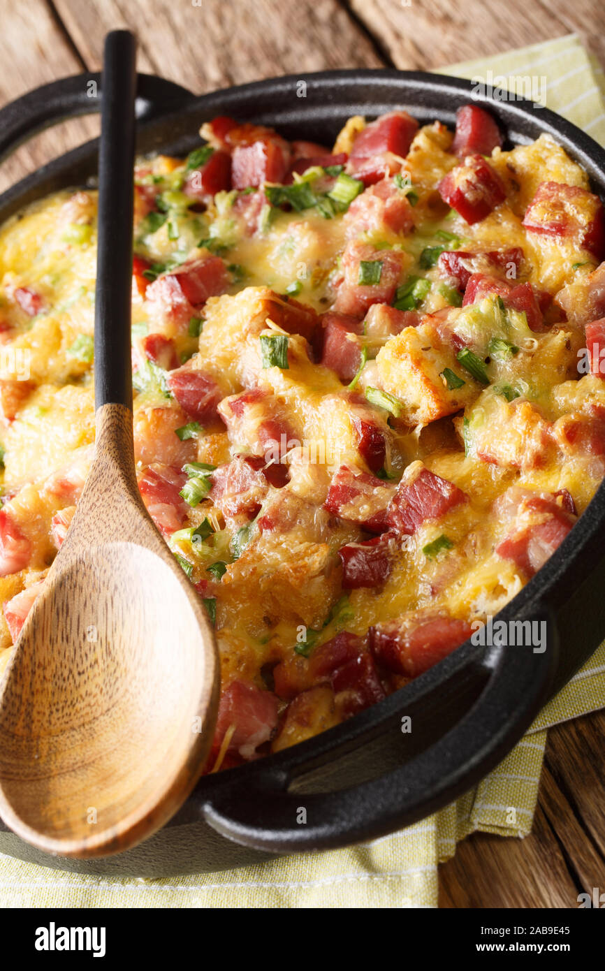 American breakfast strata con prosciutto, cipolle, formaggio e uova cotte nel forno vicino sul piano verticale. Foto Stock