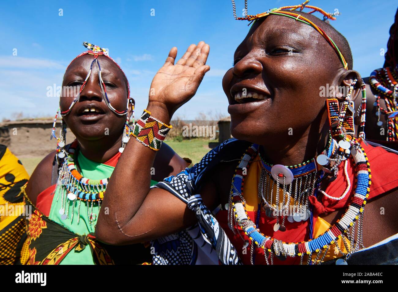 Gruppo di Massai donne cantare e ballare in abito tradizionale e adornata con cordone di lavoro, Masai Mara riserva nazionale del Kenya. Foto Stock