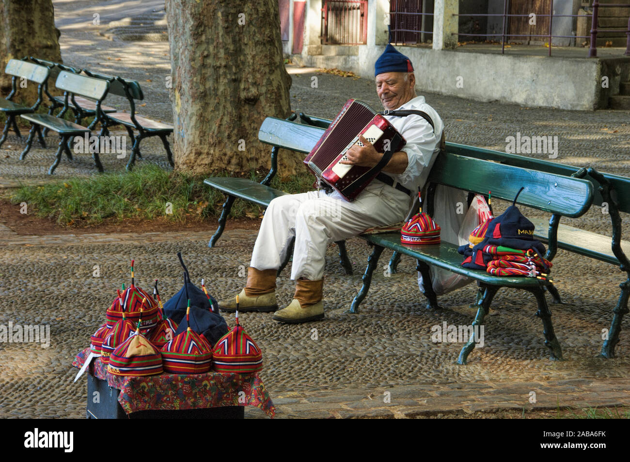 Il vecchio uomo in Madeira costume regionale suonando la fisarmonica e la vendita di tappi tradizionali a monte, Funchal, Madeira Foto Stock