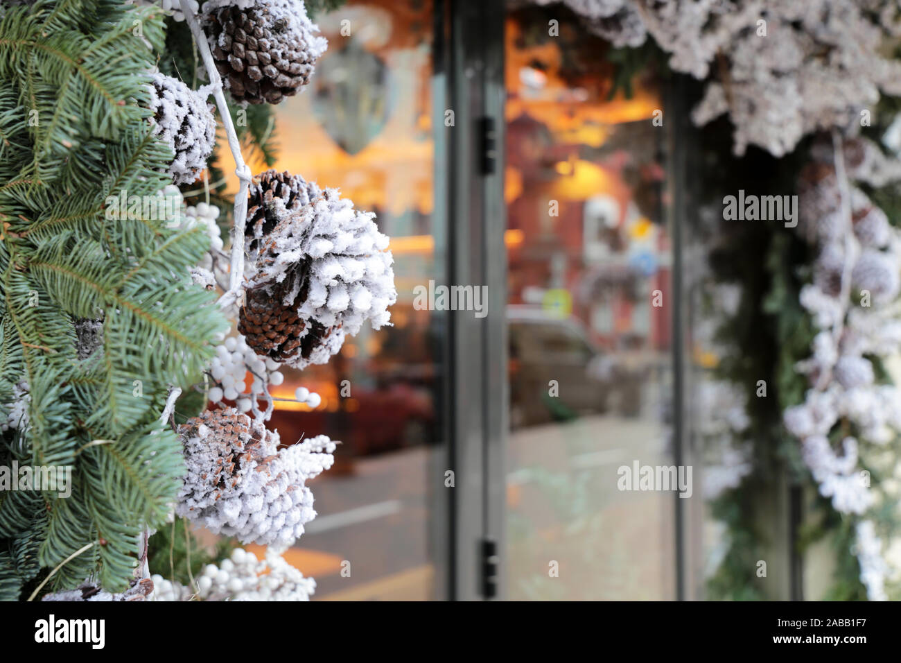 Le decorazioni di Natale in una vetrina su una strada della citta'. Rami di abete e pino coni in inverno, nuovo anno celebrazione, la magia della vacanza Foto Stock
