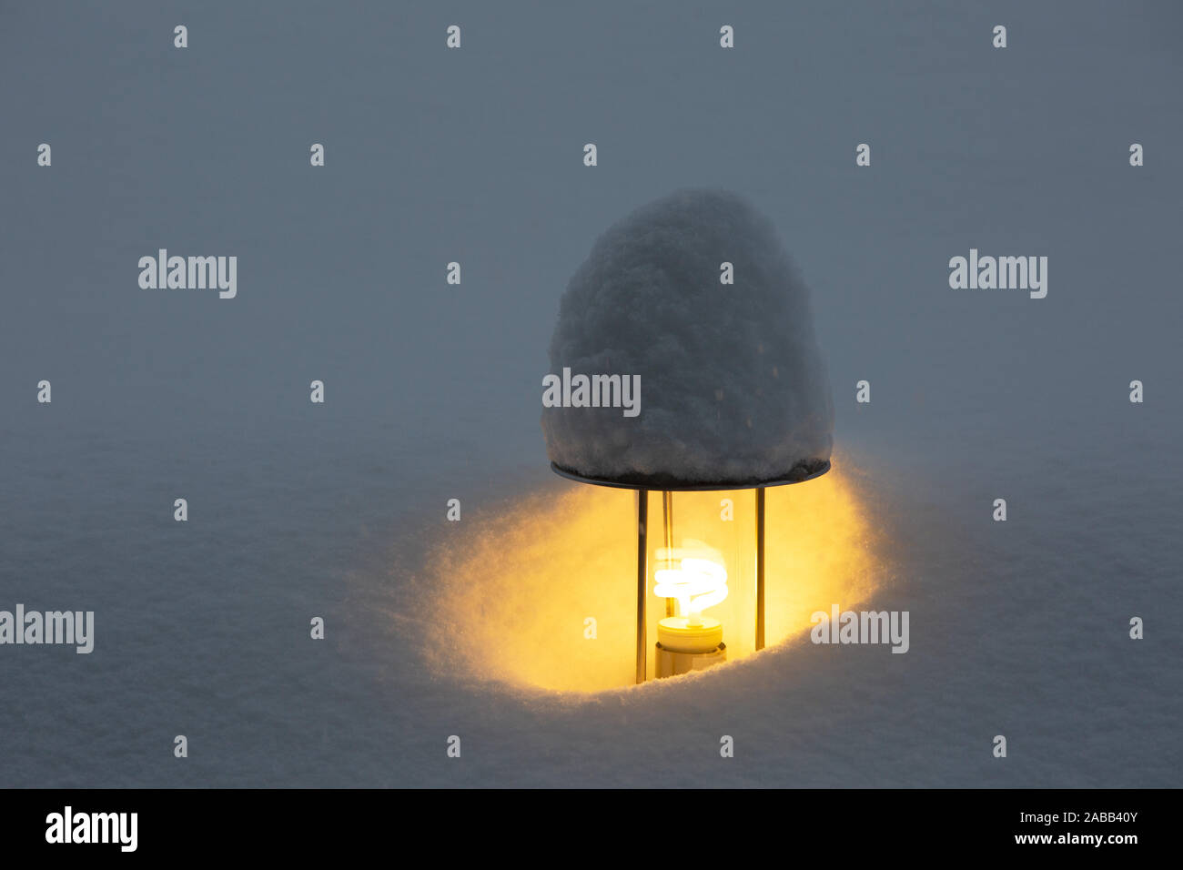 Una torcia elettrica illumina il giardino durante nevicate intense. Una lampada di strada coperta di neve crea un accogliente atmosfera festosa Foto Stock