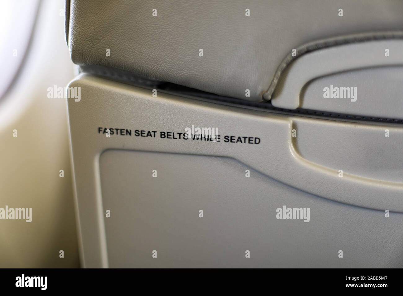 Allacciare le cinture di sicurezza mentre si è seduti - Testo sul retro di un velivolo per sedile passeggero Foto Stock