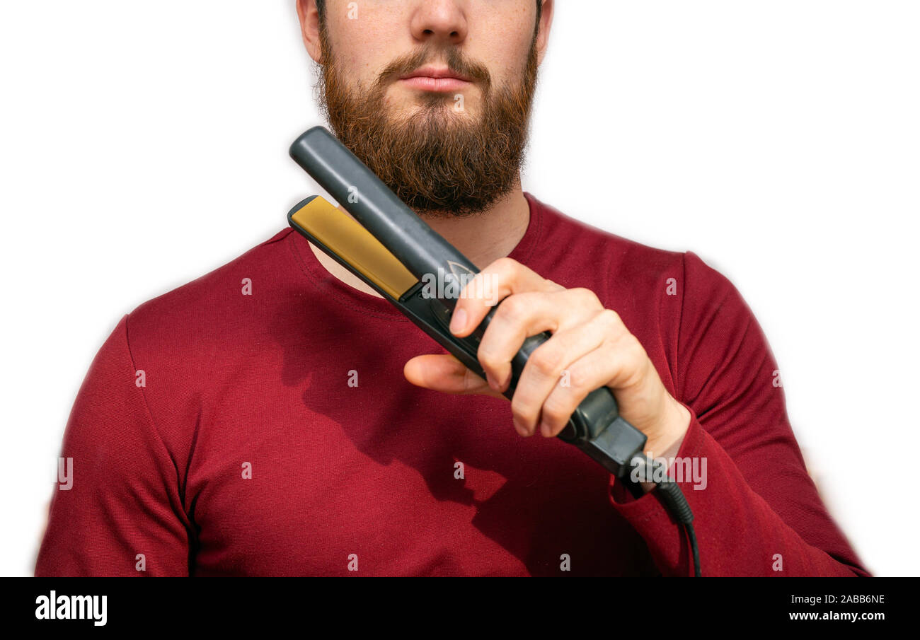 Ritratto di uomo di raddrizzare la sua barba con un raddrizzatore, lo styling della sua barba isolato su sfondo bianco Foto Stock