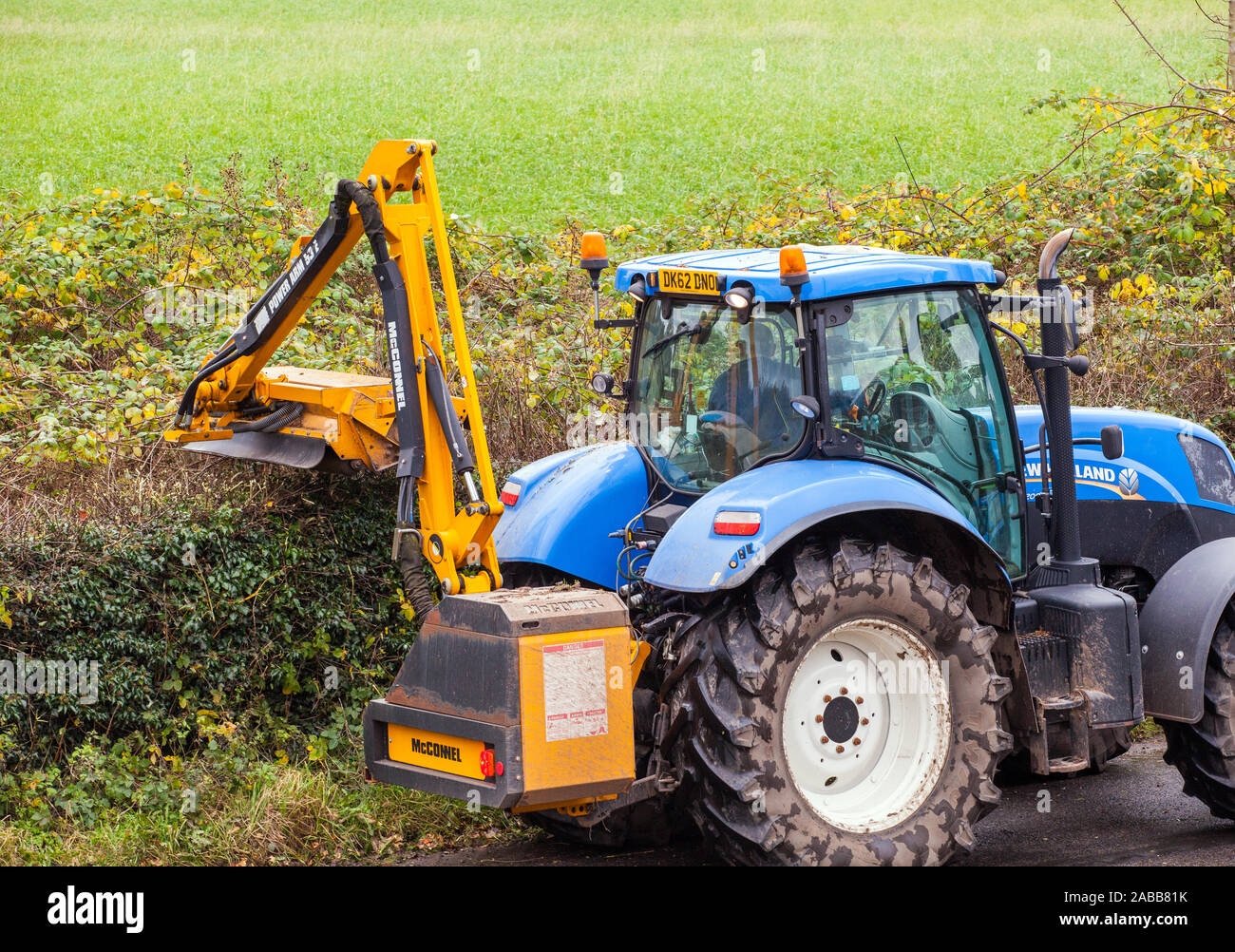 Azienda contraente agricoltore alla guida di un trattore taglio di siepi durante l'autunno con un McConnel tagliasiepi Foto Stock