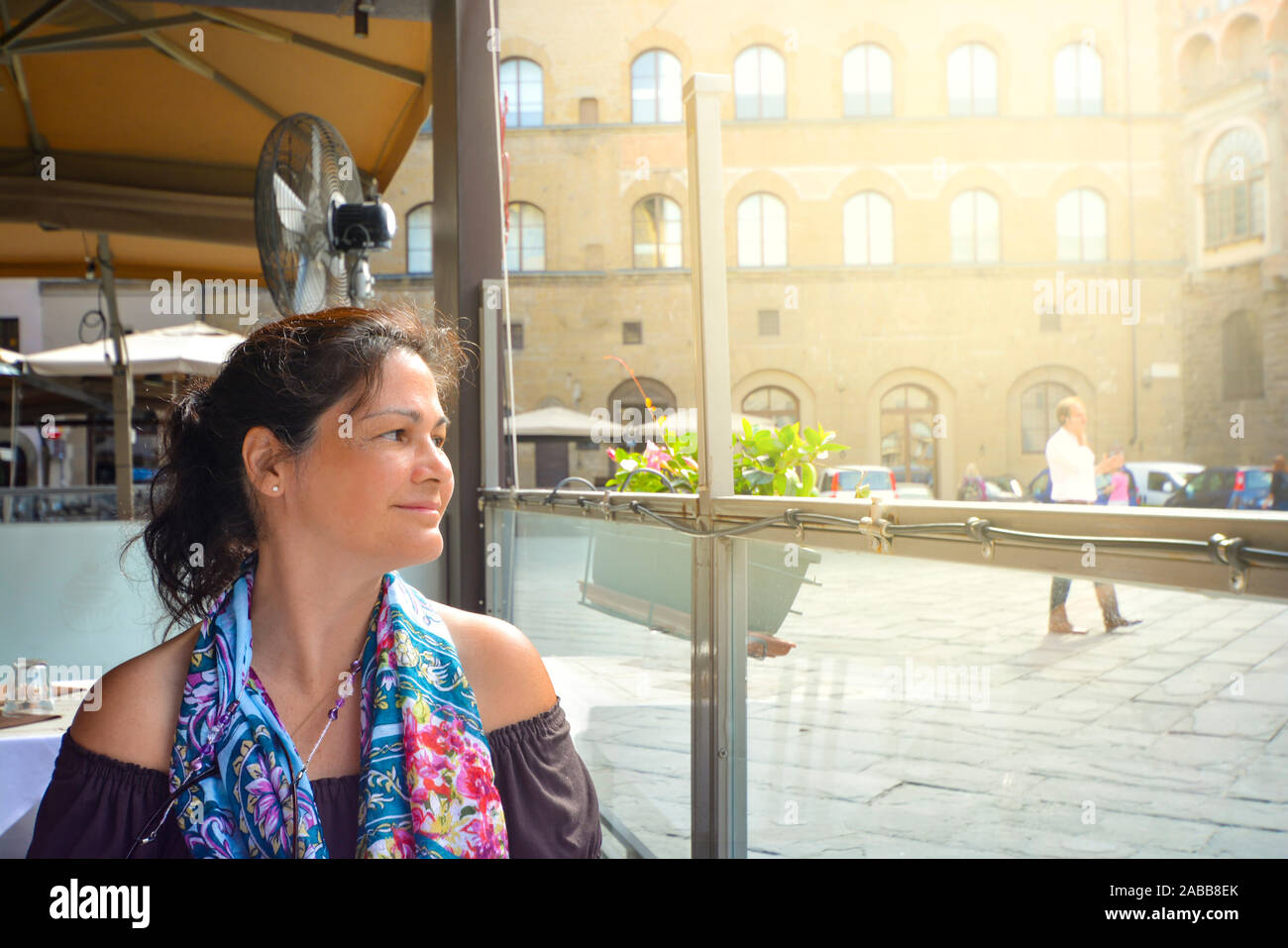 Una trentina di qualcosa di attraente brunette sguardi con apprezzamento in corrispondenza dei suoi dintorni in un cafè sul marciapiede in Firenze, Italia Foto Stock