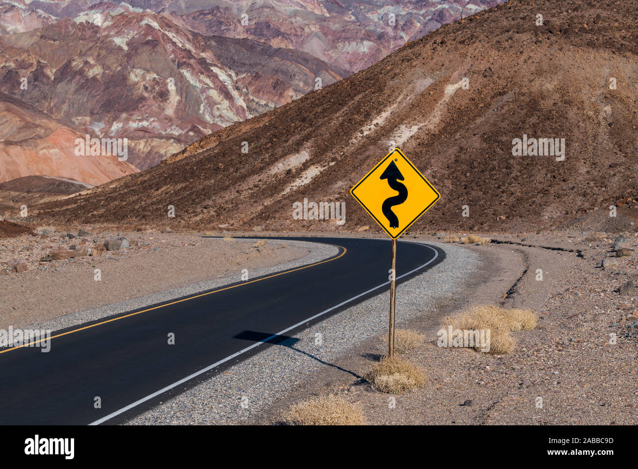 Un storto cartello stradale lungo artista della trasmissione che curva attraverso il deserto colorato paesaggio del Parco Nazionale della Valle della Morte, CALIFORNIA, STATI UNITI D'AMERICA Foto Stock