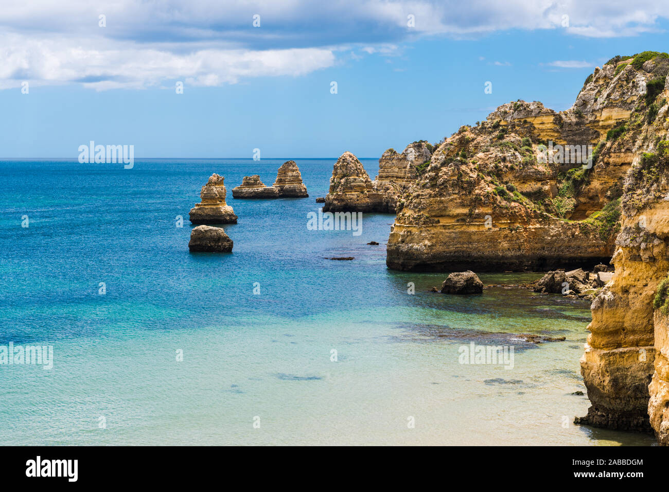 Seascape di calme acque blu e alte scogliere e formazioni rocciose a Praia da Dona Ana beach a Lagos sulla costa di Algarve in Portogallo Foto Stock