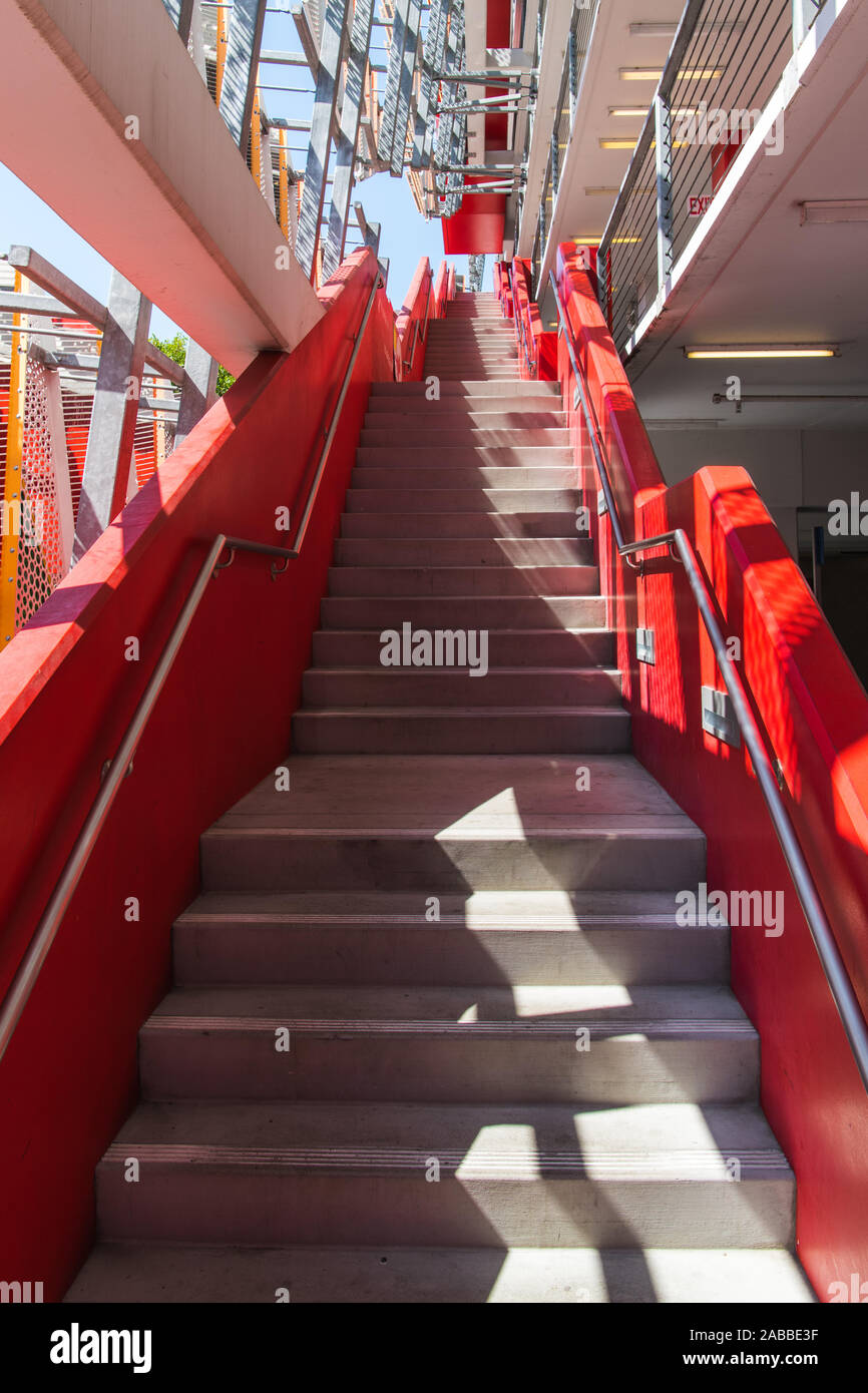 Rosso vivace scalinata in cemento con molti voli di fasi crescenti livelli multipli lungo la superficie esterna di un edificio di moderna costruzione Foto Stock