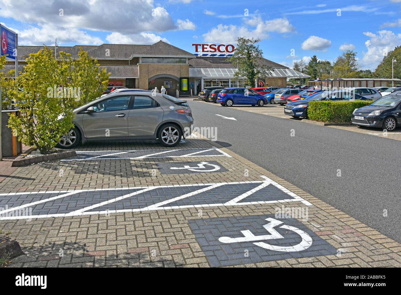 Parcheggio Disabili bay spazi al supermercato Tesco cliente parco auto icone verniciati sul blocco di pavimentazione città di Ely Cambridgeshire East Anglia England Regno Unito Foto Stock