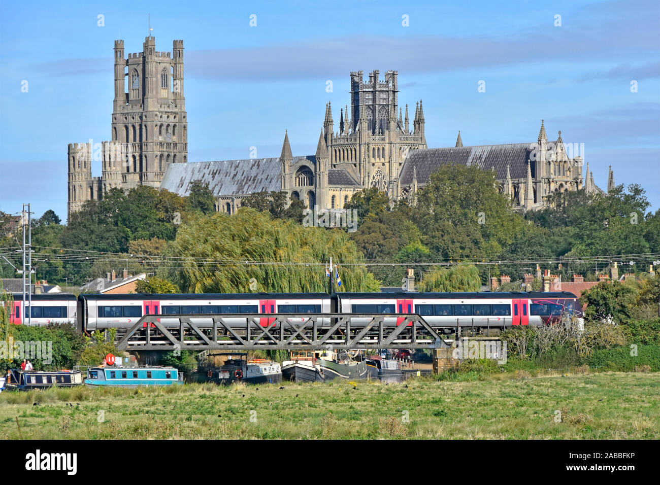 Cattedrale di Ely al di là di treno in partenza Stazione di Ely Cambridgeshire barche sul Fiume Great Ouse sotto il ponte ferroviario East Anglia Fens paesaggio England Regno Unito Foto Stock