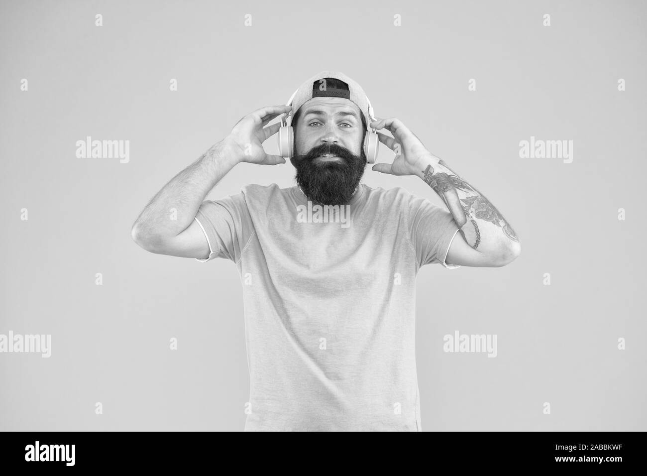 Cuffie con design ergonomico. Tanga regolabile da indossare cuffie bianche su sfondo giallo. Uomo Barbuto ascoltando musica in cuffia stereo. Ragazzo caucasico utilizzando cuffie wireless bluetooth. Foto Stock