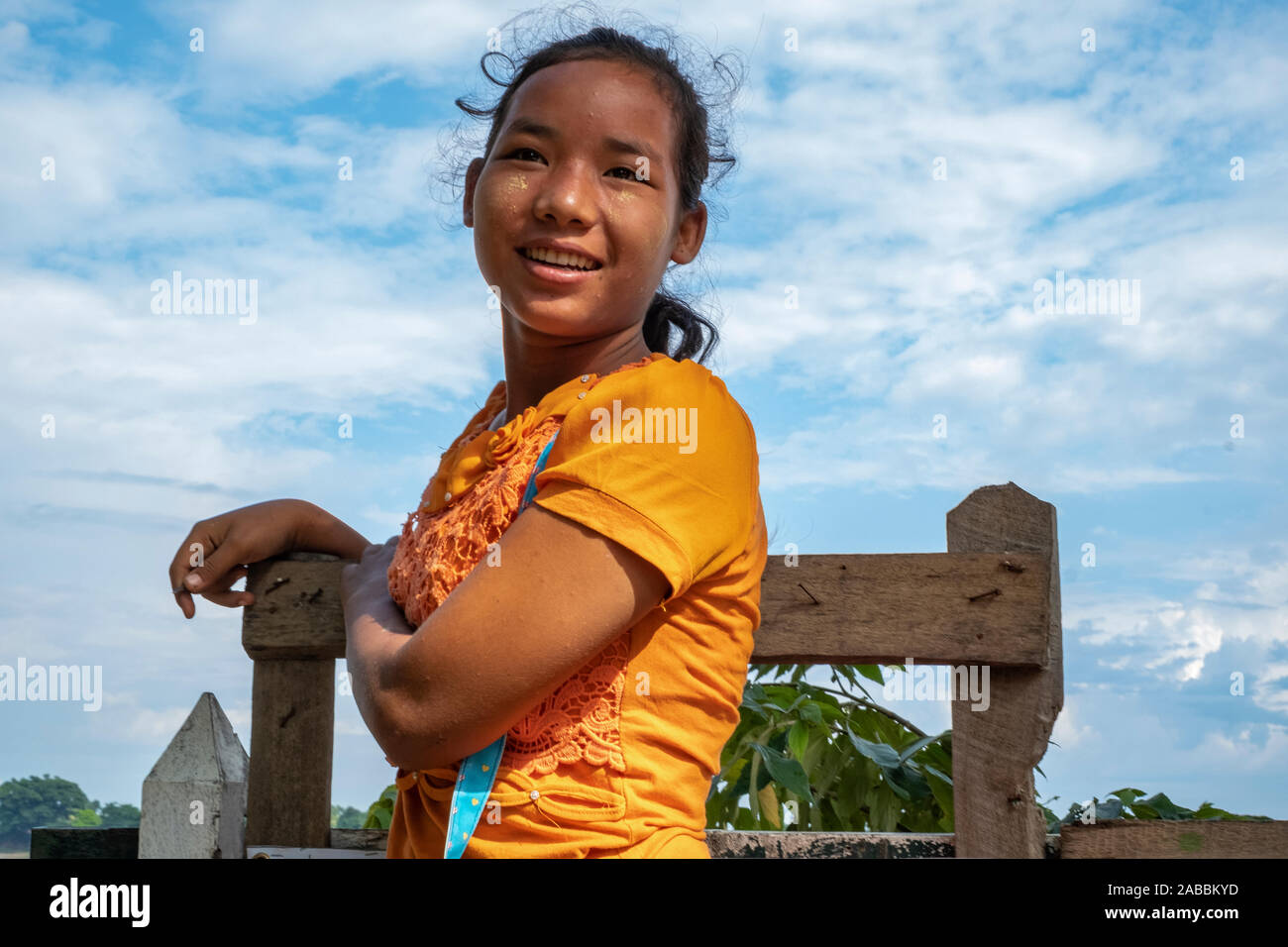 Giovane e bella ragazza birmano in un giallo brillante camicetta attende di salire a bordo di un taxi acqueo in Kanne villaggio sul fiume Chindwin in Myanmar (Birmania) Foto Stock