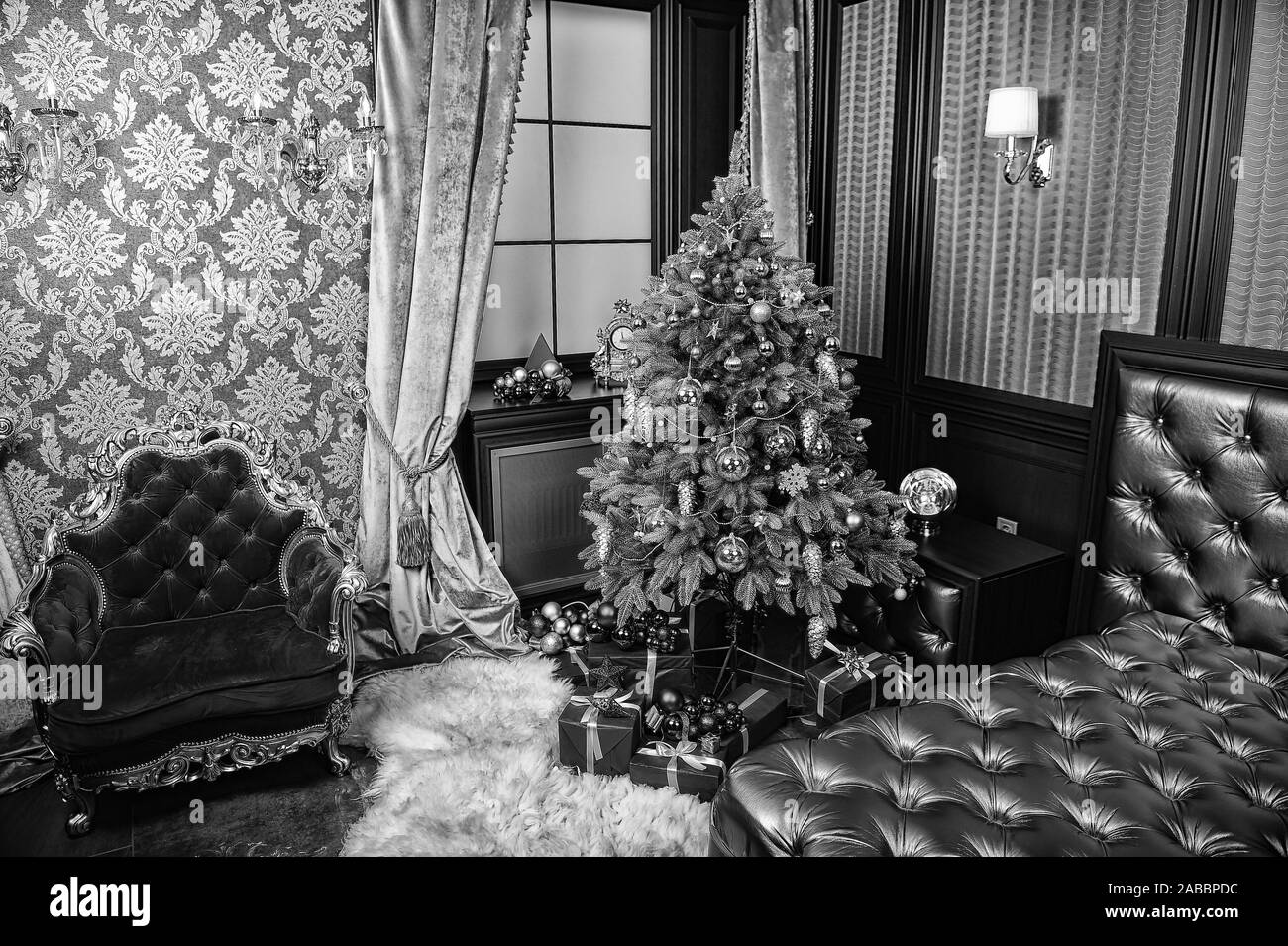 Albero di natale, presente scatole, poltrona rossa e dorata divano nel soggiorno. Nuovo anno e xmas room interior concept. Festive decorazioni e ornamenti. Vacanze invernali celebrazione. Foto Stock