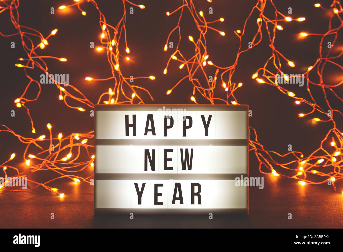 Felice Anno Nuovo cinema a tema luce casella sul tono scuro dello sfondo con ghirlande di luci Foto Stock