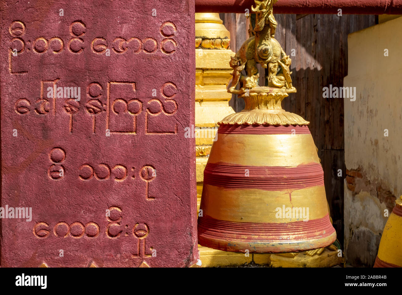 Dipinto di tempio Buddista campana con una preghiera inscritto in script birmano su di una parete di supporto della campana in Kanne village, Chindwin River, Myanmar (Birmania) Foto Stock