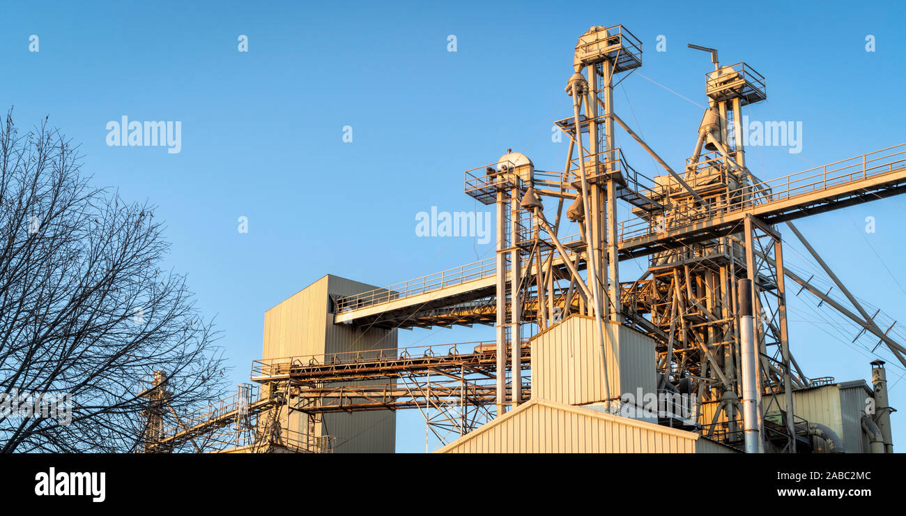 Panorama industriale abstract - parte superiore di un elevatore granella con un flusso a gravità tubi contro il cielo blu Foto Stock