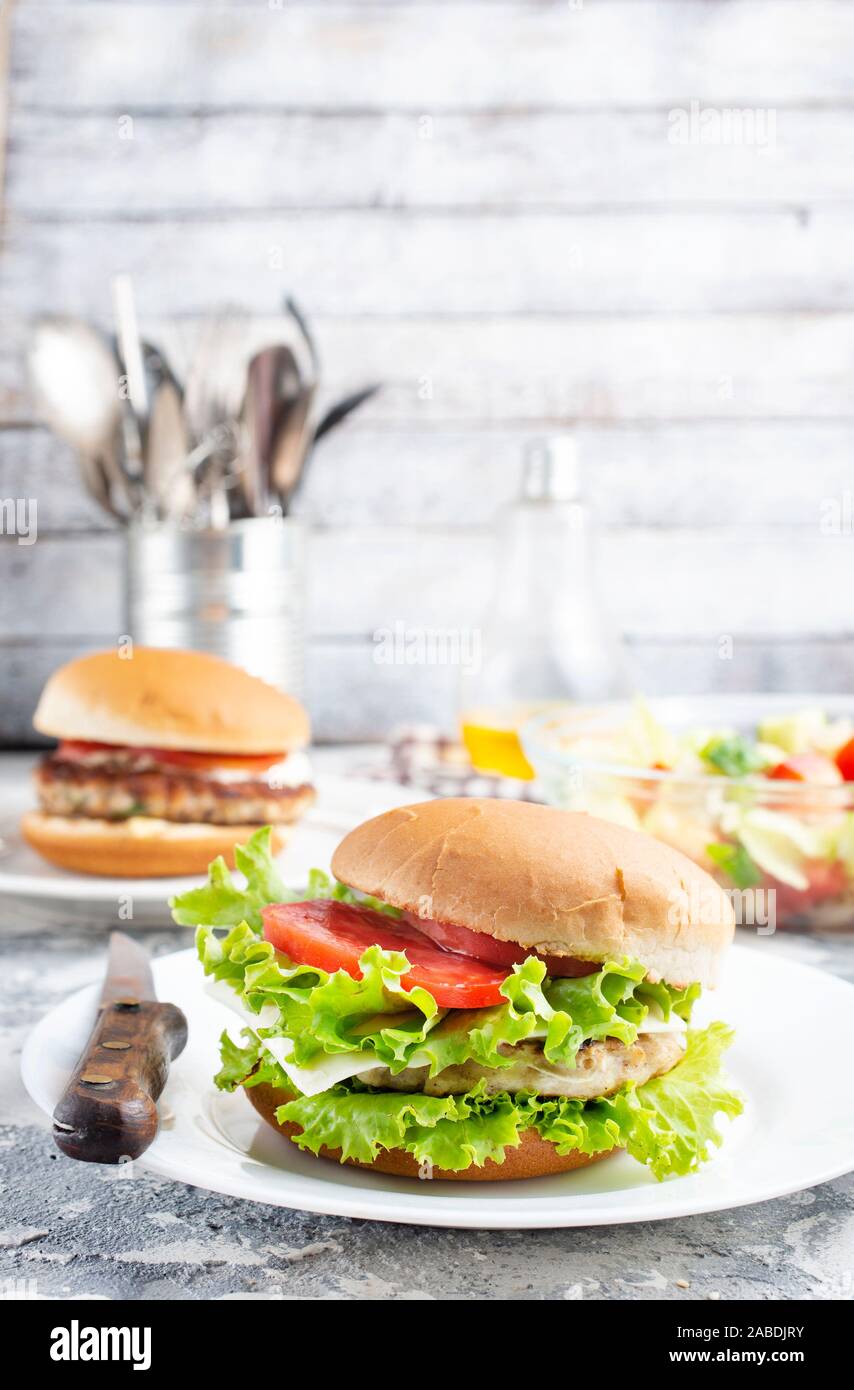 Hamburger di pollo close up su una piastra bianca. Burger, formaggio,  lattuga, pancetta, pomodoro e salsa bianca Foto stock - Alamy