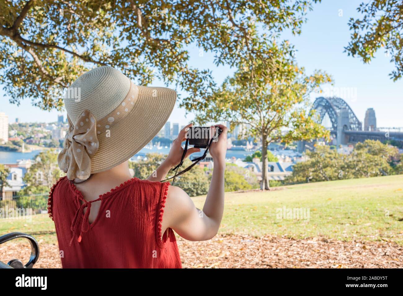 Donna seduta su una panchina in un parco e guardando il Ponte del Porto di Sydney Foto Stock