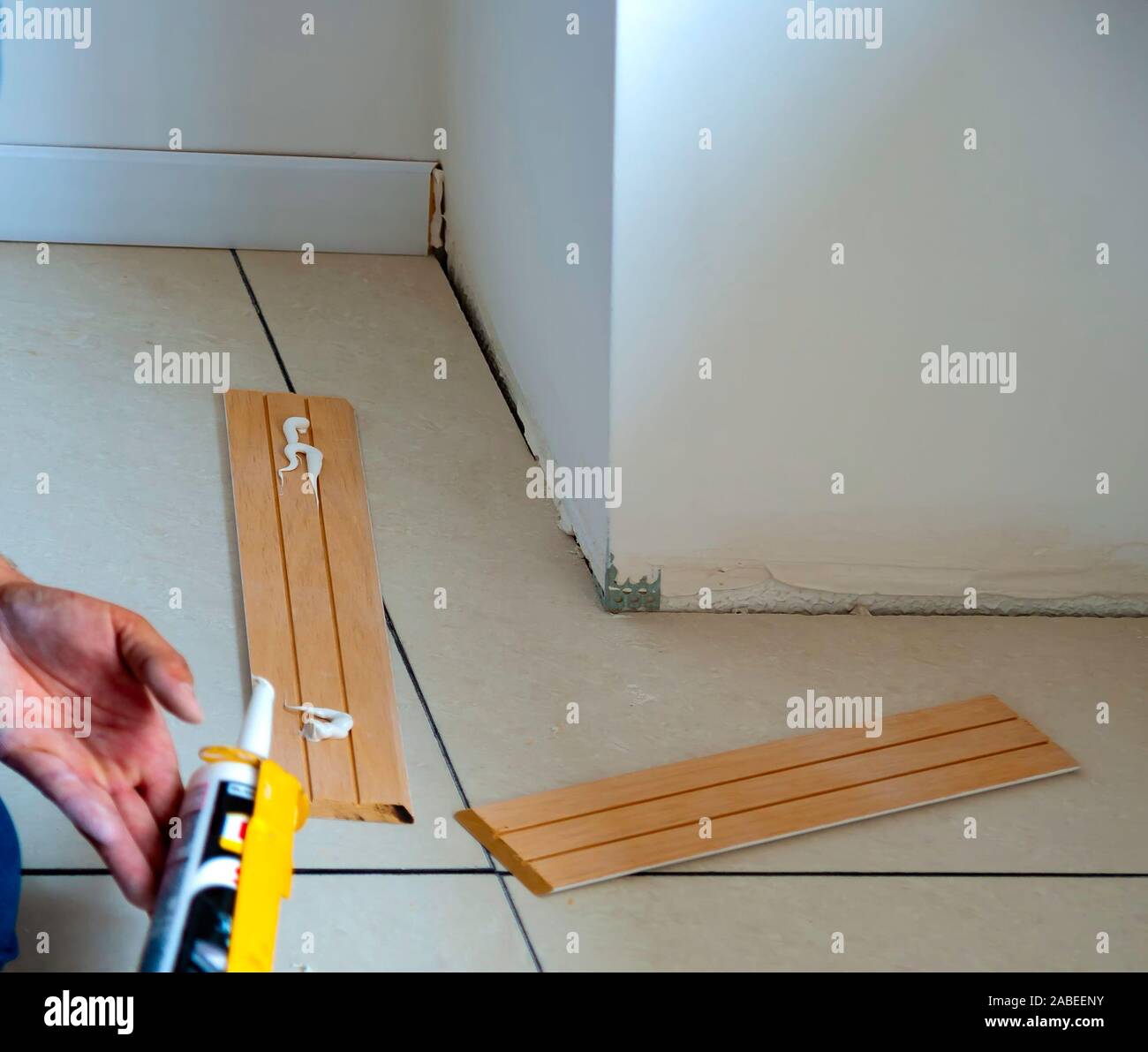 Lavoratore si applica colla su legno battiscopa per montaggio a parete Foto Stock