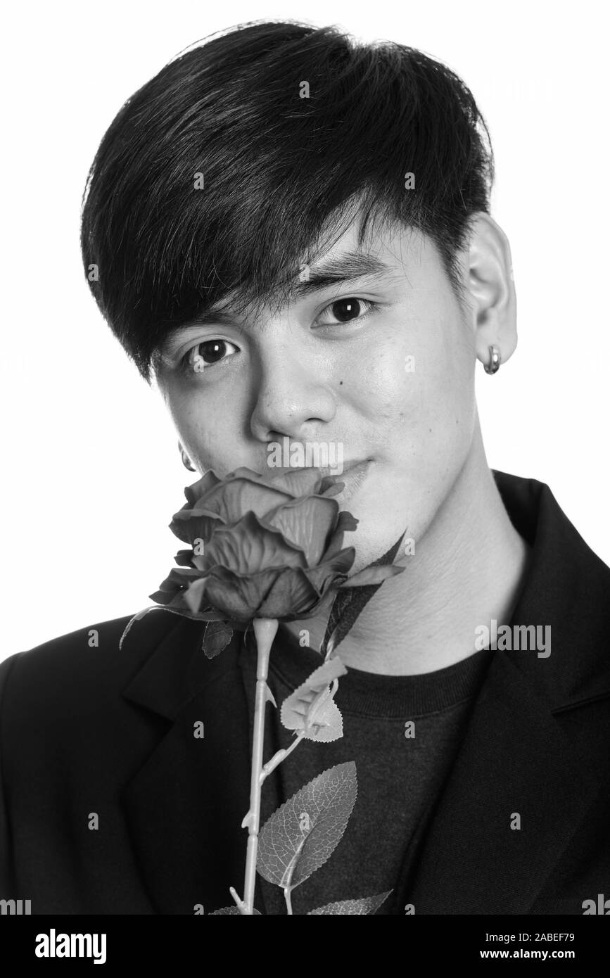 Faccia di cool bello imprenditore asiatici odore di rose rosse Foto Stock