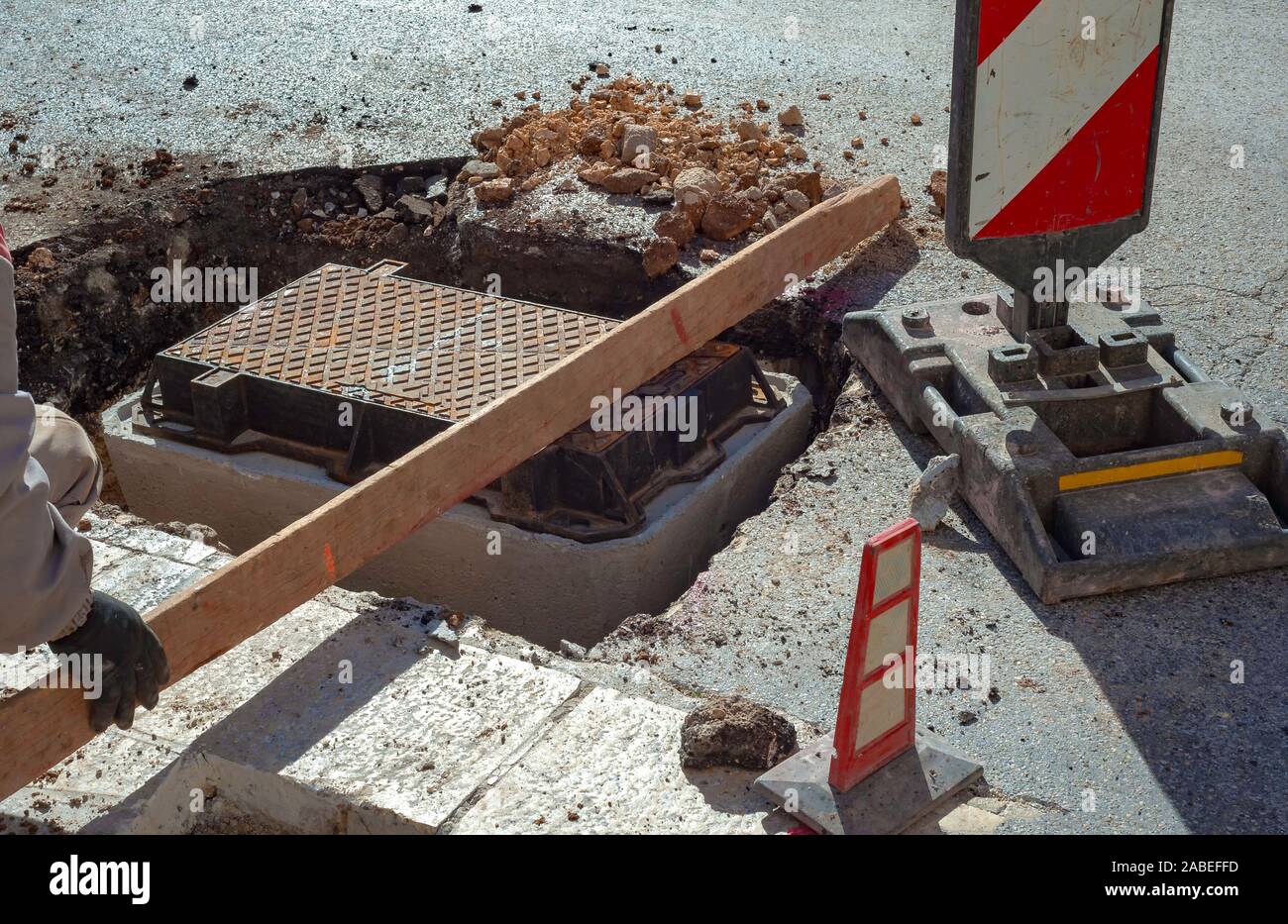 Esecuzione di fibra ottica della rete di distribuzione per le telecomunicazioni. Posizione dei lavoratori la ghisa chiusini su tombini Foto Stock