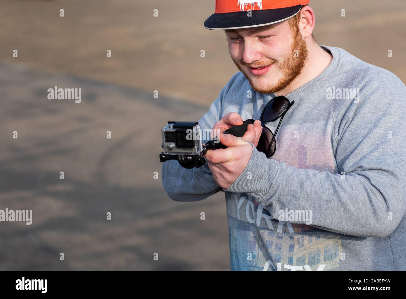 Un giovane ragazzo adolescente acquisisce il materiale dei suoi amici lo skateboard a Stoke Plaza skatepark mediante una azione di GoPro telecamera e extender Foto Stock