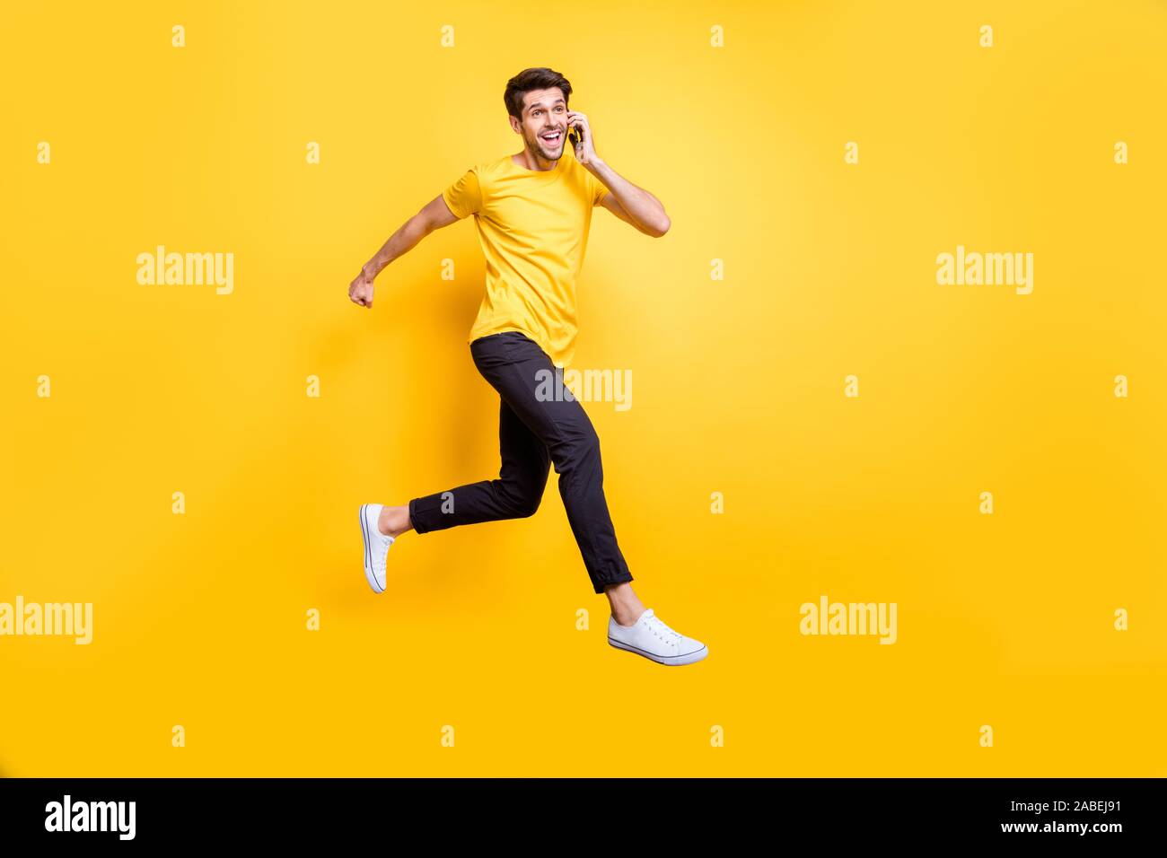 Sto sul mio modo di Darling. Foto completa del corpo di bello ragazzo jumping alta parlando telefono rushing romantico usura data t-shirt casual pantaloni isolato Foto Stock