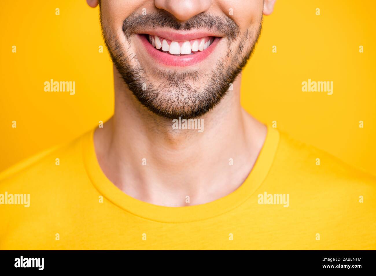 Closeup foto ritagliata di sorprendenti macho guy guardando lo specchio di esaminare i denti dopo laser dentali usura pulizia t-shirt casual isolato di colore giallo Foto Stock
