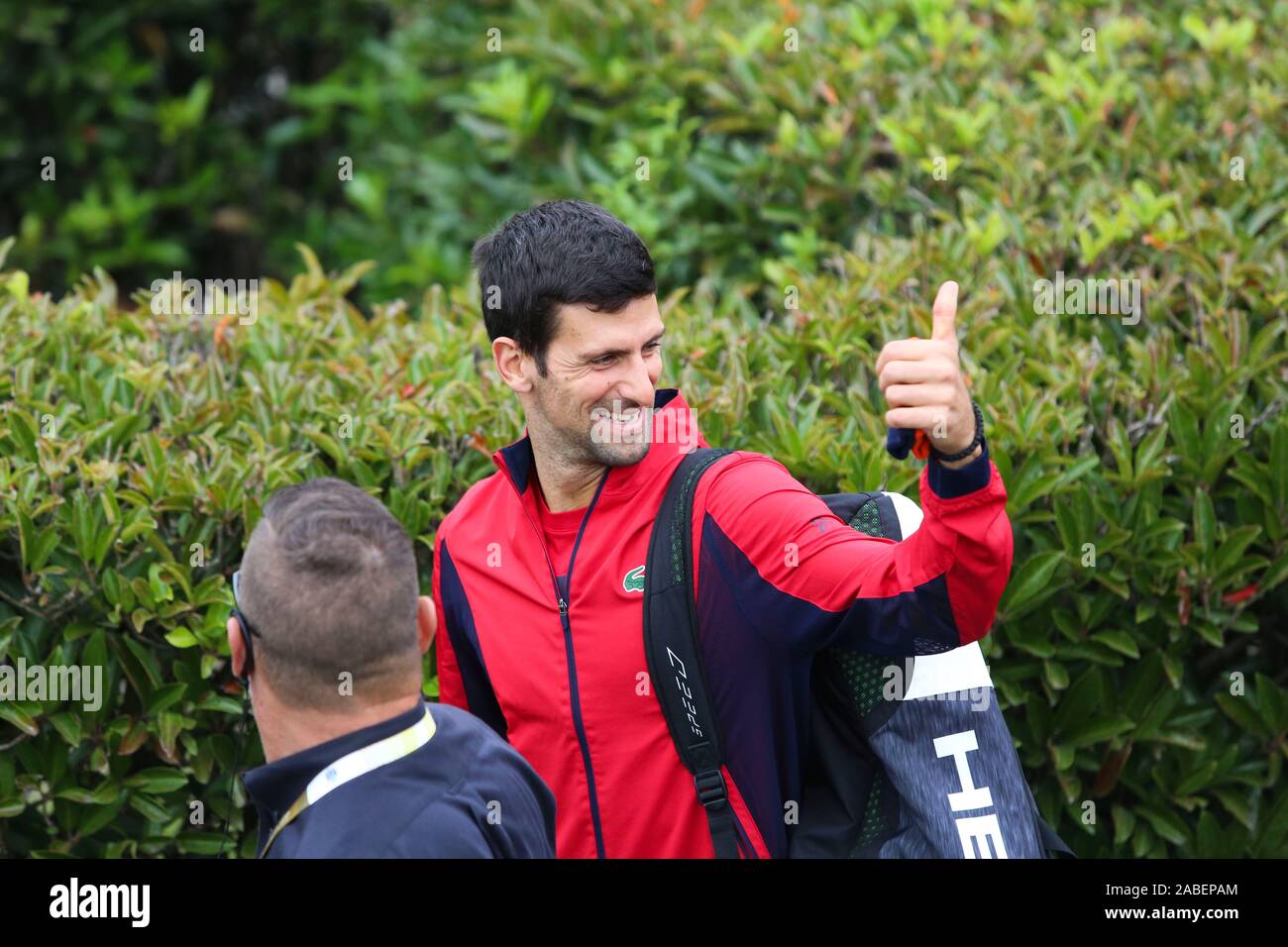 Il serbo giocatore di tennis professionista Novak Djokovic, quello in rosso, è circondato da sicurezza e tifosi locali per il suo modo di preparare per uomini doppio Foto Stock