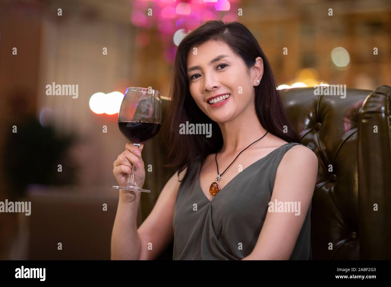 Donna elegante godendo di vino rosso in un ristorante occidentale Foto Stock