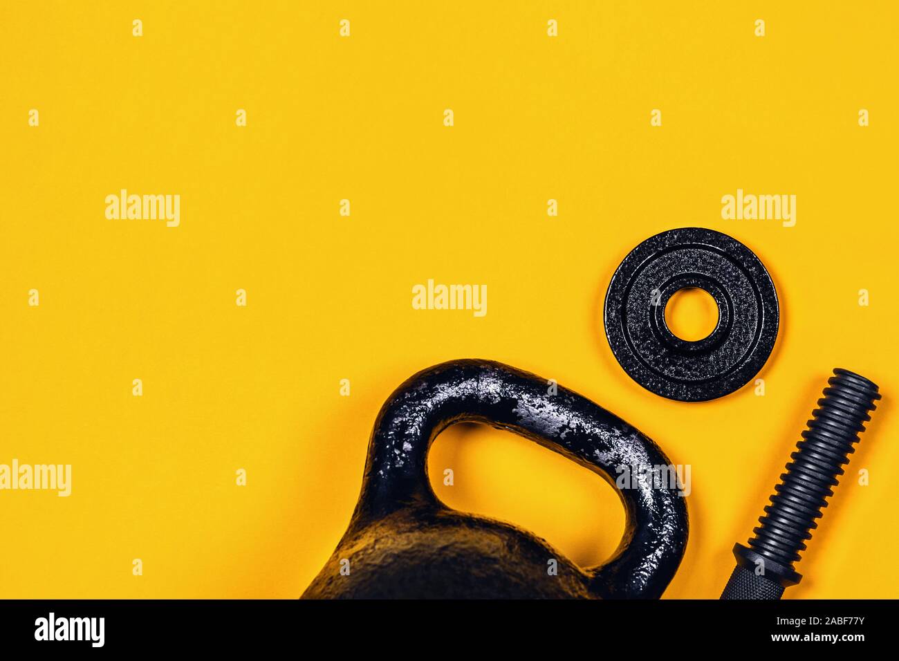 Sfondo di sport. Kettlebell e un manubrio su sfondo giallo. Appartamento laico, vista dall'alto, copia dello spazio. Foto Stock