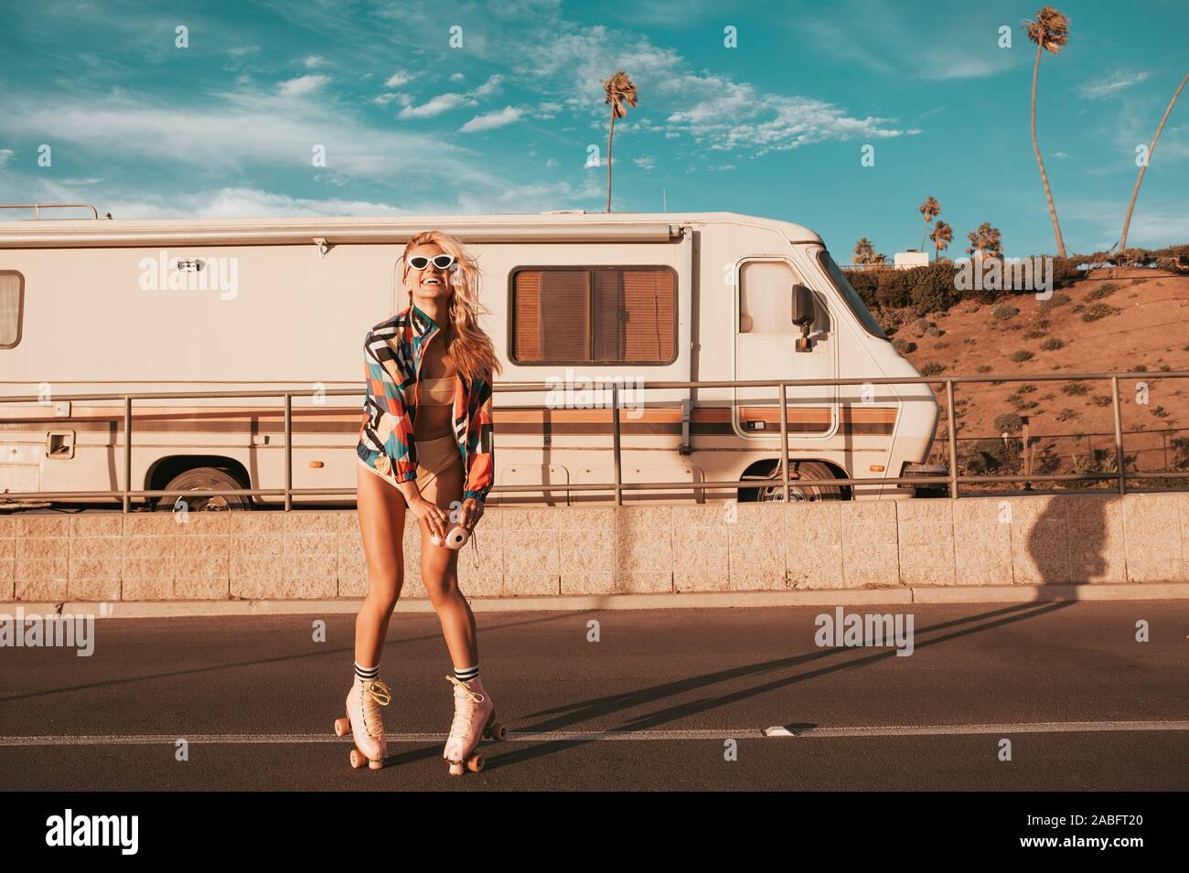 In stile retrò skater ragazza con un camper in background. california lifestyle Foto Stock