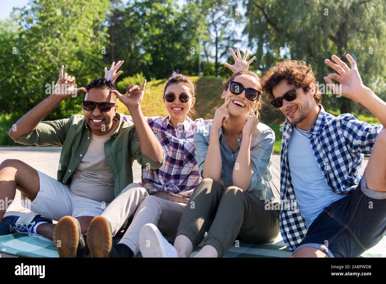 Happy amici rendendo volti al summer park Foto Stock