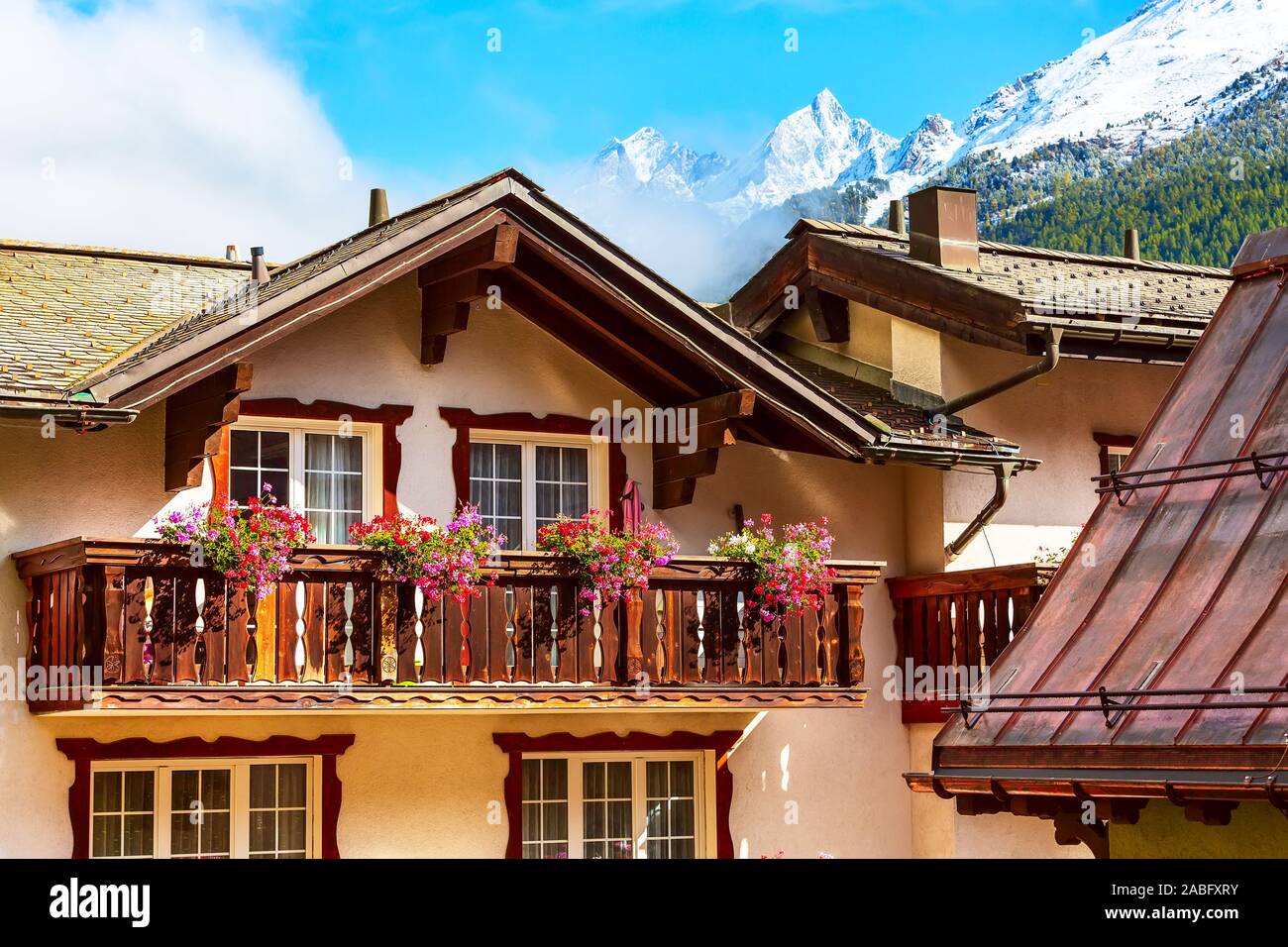 Alpi svizzere in Svizzera, casa balcone in legno decorato con fiori e picchi innevati in Zermatt Foto Stock