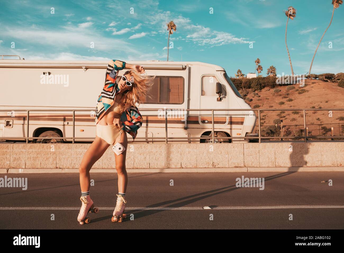 In stile retrò skater ragazza con un camper in background. california lifestyle Foto Stock