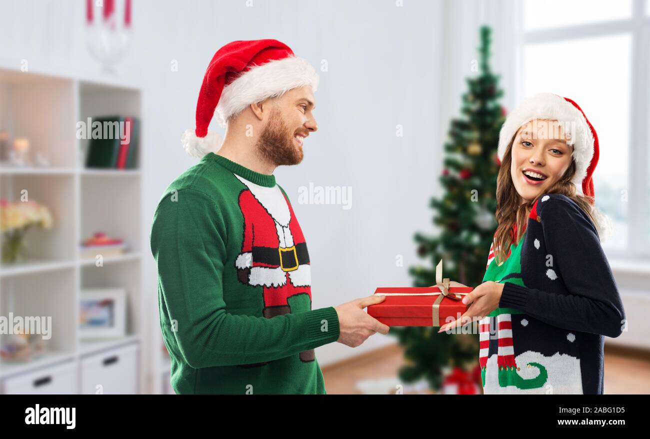 Coppia felice in brutta maglioni con regalo di natale Foto stock - Alamy