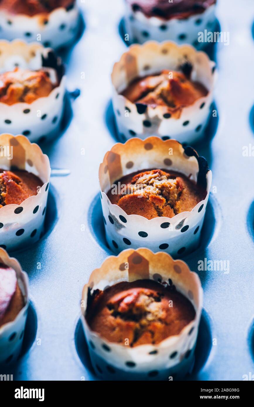 In prossimità di alcuni appena sfornato di zucca muffin rivestiti su un alluminio vassoio da forno per la Festa di halloween visualizzata su un blu scheda rustico, laici piatta vista dall'alto,nat Foto Stock