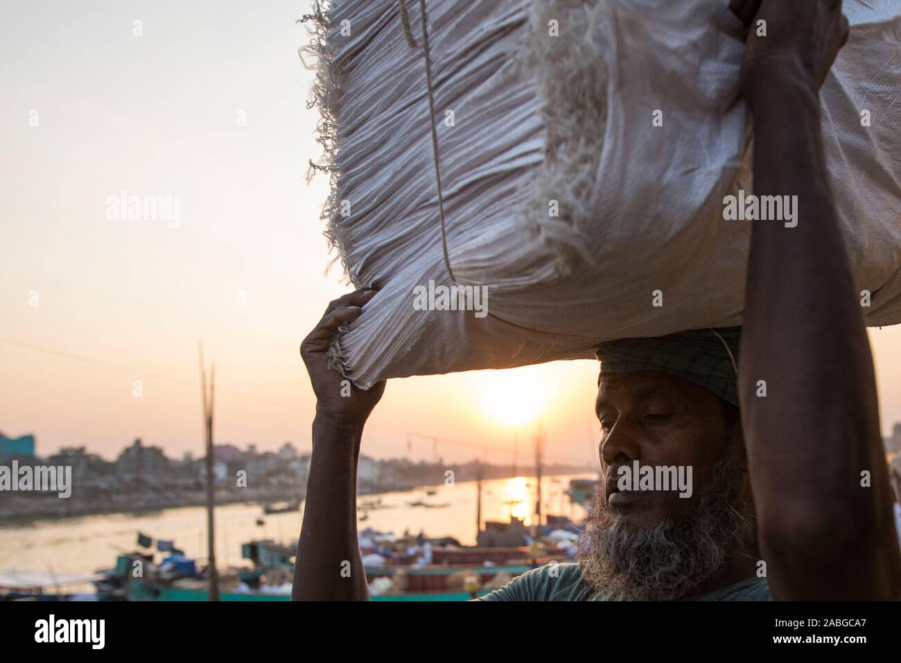 Dacca in Bangladesh - Novembre 27, 2019 : Operaio il caricamento di merci in barca nel fiume Burigana. Foto Stock