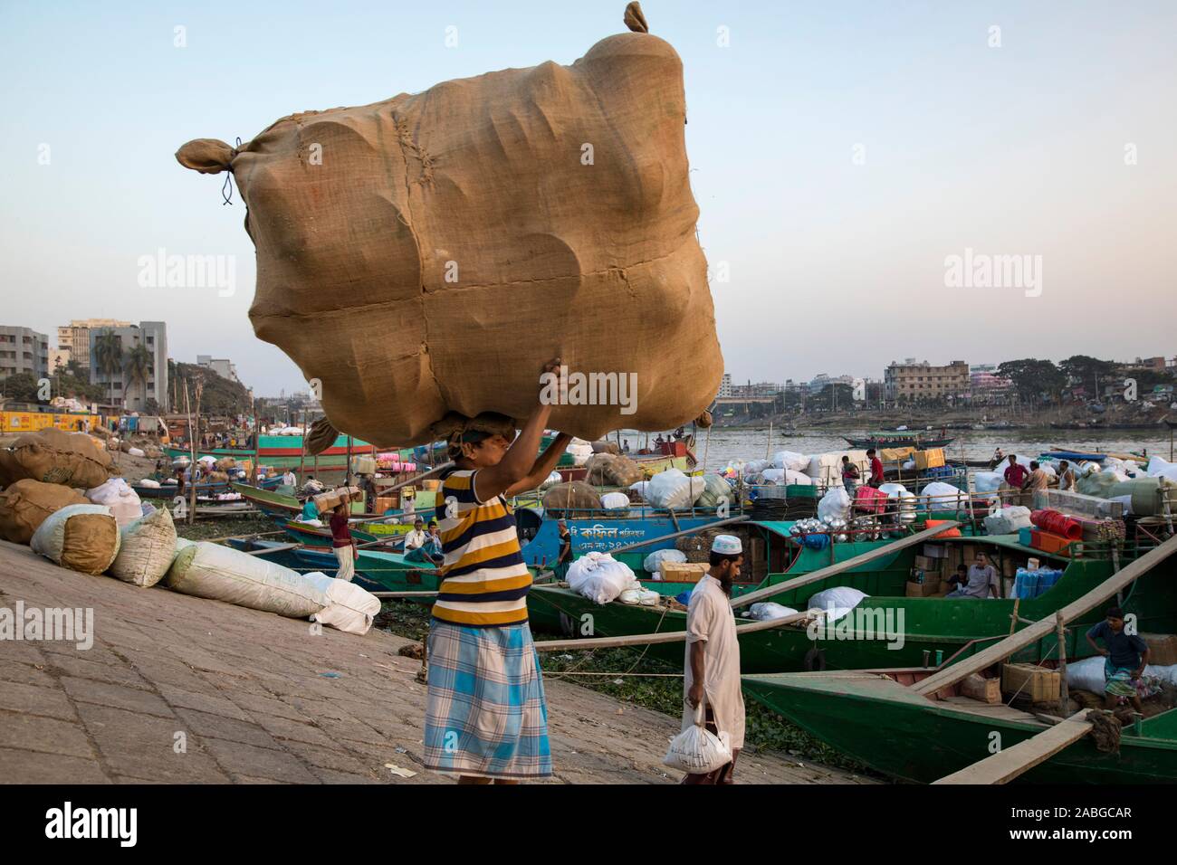 Dacca in Bangladesh - Novembre 27, 2019 : Operaio il caricamento di merci in barca nel fiume Burigana. Foto Stock