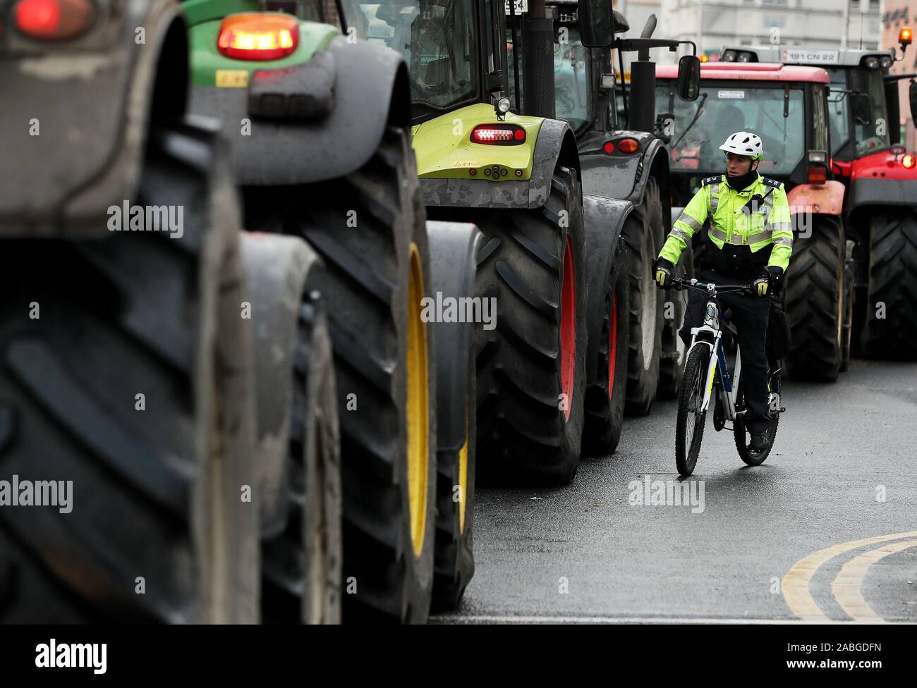 Un membro di un garda passa i trattori parcheggiati nelle strade intorno a Santo Stefano verde nel centro della città di Dublino come una manifestazione di protesta da parte degli agricoltori al di sopra dei prezzi da ottenere per i loro prodotti continua. Foto Stock