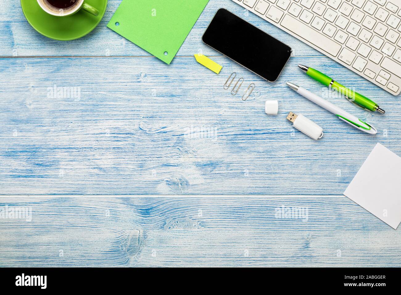 Sfondo con la tastiera del computer, smart phone, tazza di caffè e utensili disposti su blu scrivania in legno. Copia di grandi dimensioni spazio. Foto Stock